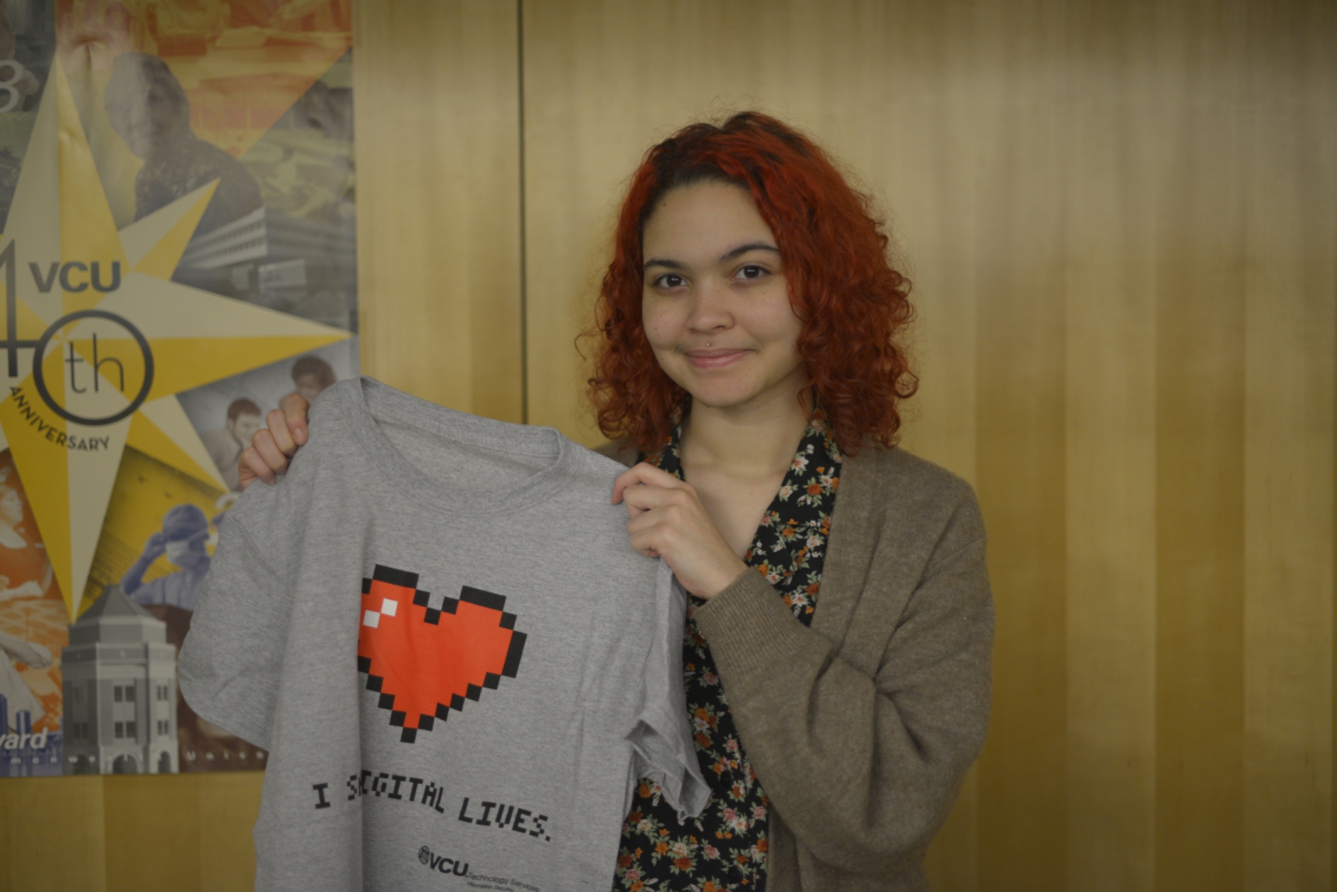 Photo of Levi Walters holding a grey I save digital lives tee.